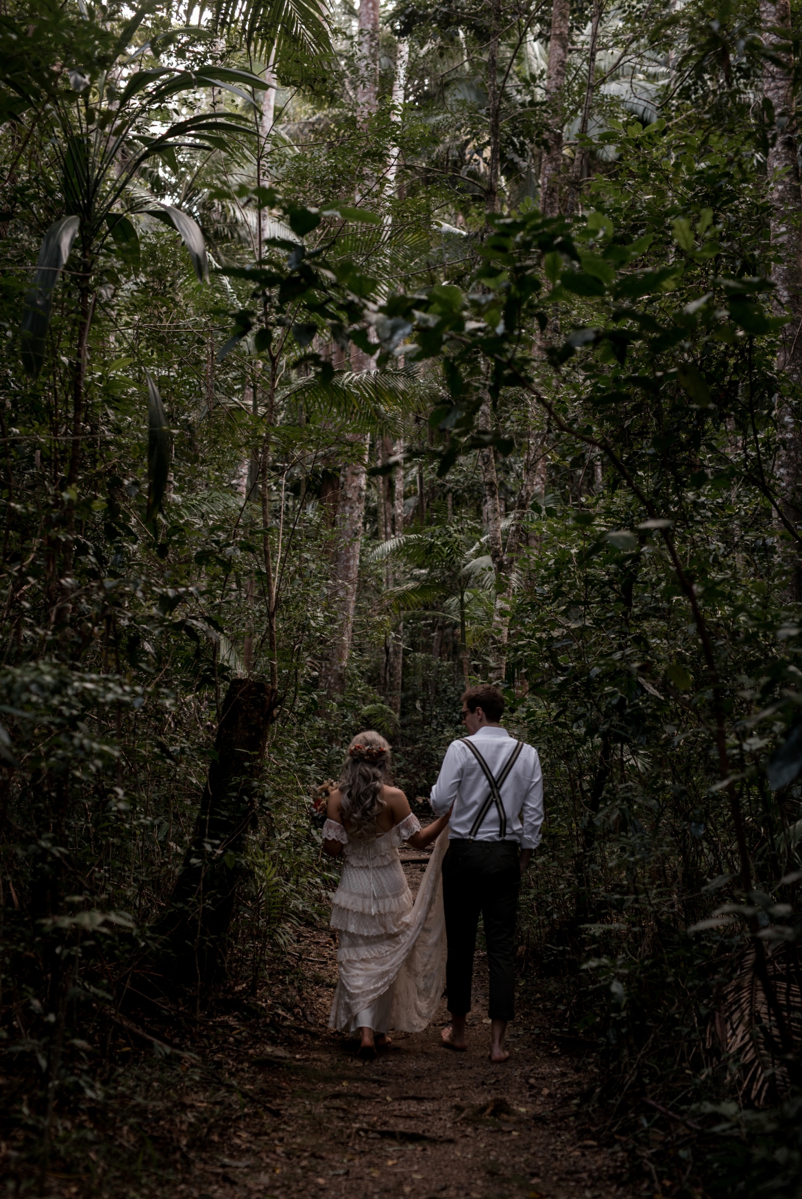 the wedding couple  walking away down a path at Crystal creek rainforest retreat elopement with bohoelope
