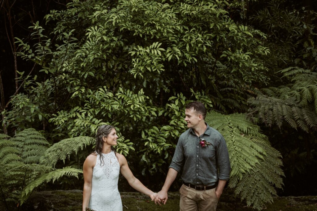 The bride and groom standing next to each other holding hands and smiling at Crystal creek rainforest retreat, NSW. CCRR