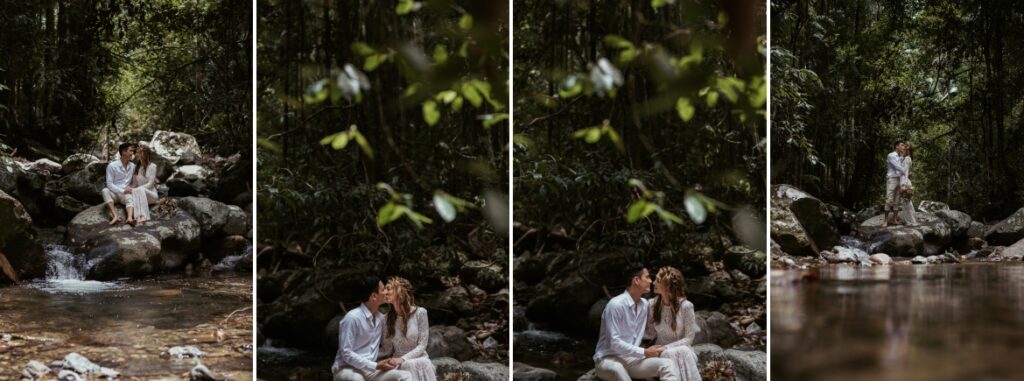 The bride and groom having a romantic moment in the creek sitting on huge boulders at crystal creek rainforest retreat. CCRR