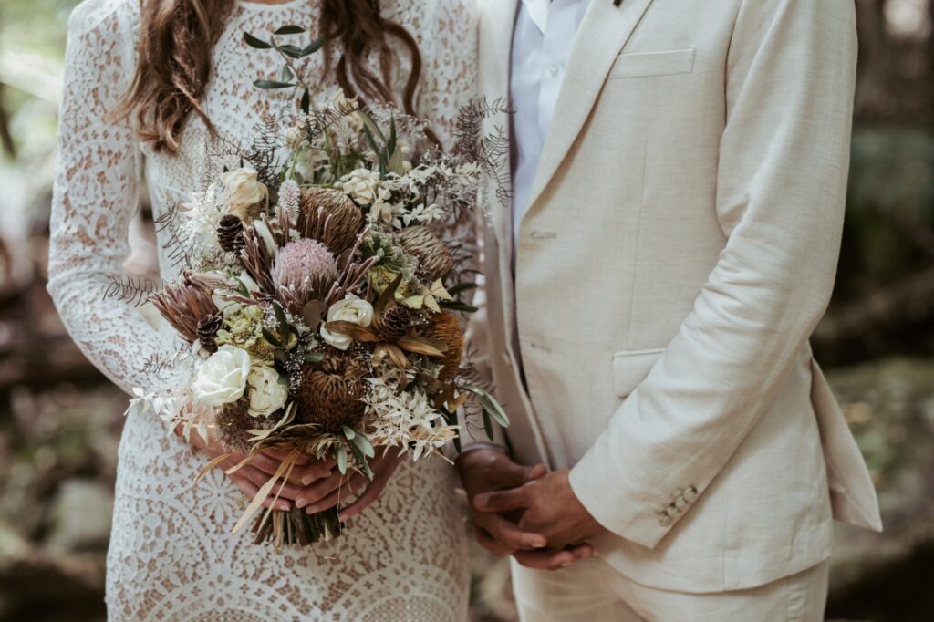 A close up photo detail of the bride and groom standing side by side with the bride holding the bouquet in front of her at crystal creek rainforest retreat. CCRR