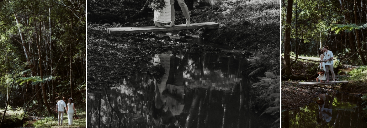 A couple walking and standing on a little foot bridge across a tiny creek and sharing a kiss at the forest stone circle ceremony spot at Bunyarra in Crystal Creek NSW